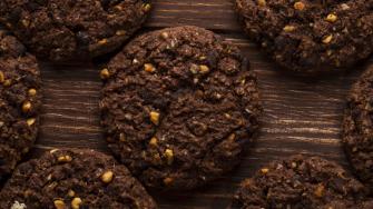 top view of chocolate chip cookies with cereals nuts and cocoa on wooden background